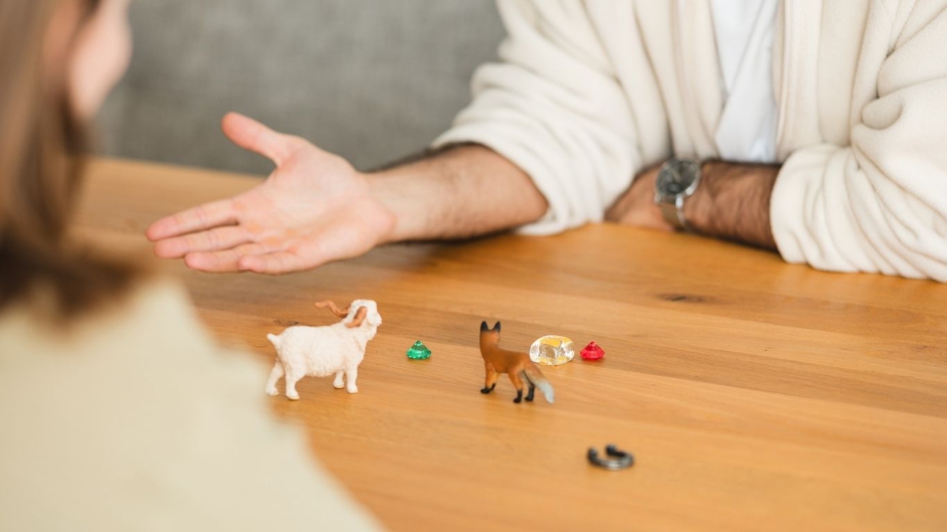 Hand zeigt auf kleine Tierfiguren auf einem Holztisch